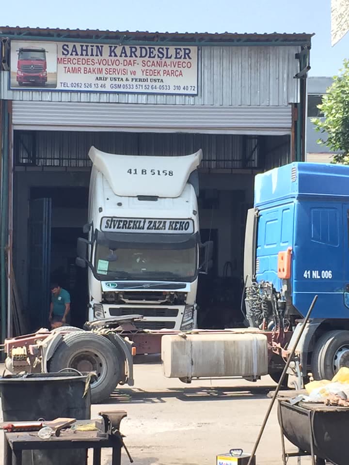 Atölye girişinde beyaz bir çekici ve tabela